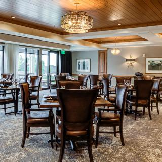An elegant dining area with wooden tables and chairs, featuring a decorative chandelier.