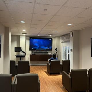 A comfortable lounge area with a large television and seating, designed for meetings or presentations.