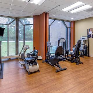 A modern fitness center with various exercise equipment and large windows.