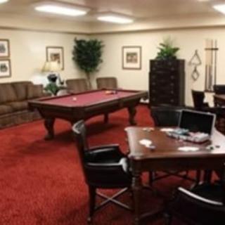 A well-furnished game room featuring a pool table and a poker table.