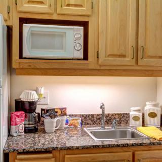 A small kitchen area with a microwave, coffee maker, and sink on the countertop.