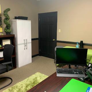 A neatly arranged office space featuring a desk with a computer, a refrigerator, and decorative elements.