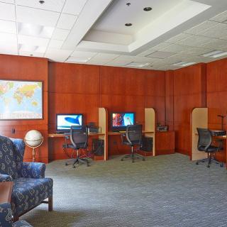 A quiet office space with multiple computer workstations, wooden paneling, and a map on the wall.