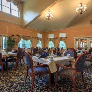 An elegant dining room with neatly arranged tables and classic chandeliers.