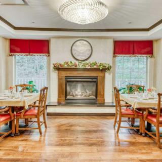 An elegant dining room featuring a cozy fireplace, chandelier, and arranged tables and chairs.