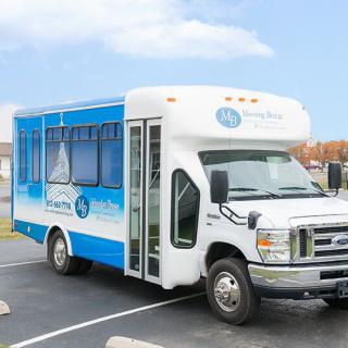 A blue and white shuttle bus parked in a parking lot.