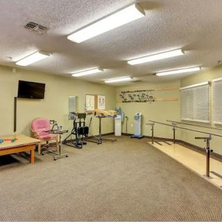 A rehabilitation room equipped with parallel bars and various exercise machines.