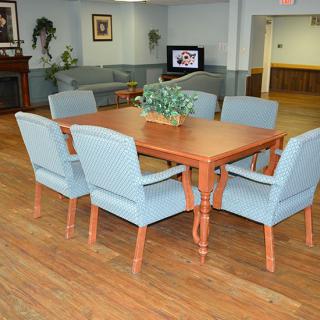 A neatly arranged dining room with a wooden table and blue upholstered chairs on a hardwood floor.