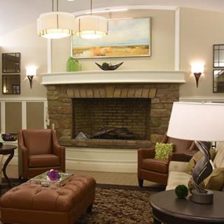 A stylish and cozy living room featuring a stone fireplace, leather chairs, and elegant decor.