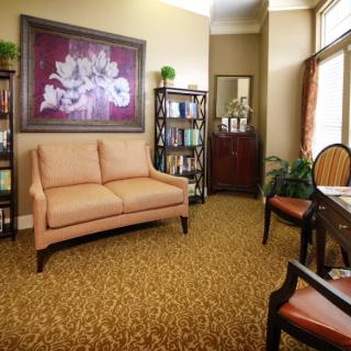 A cozy living room with a sofa, bookshelves, and floral artwork.