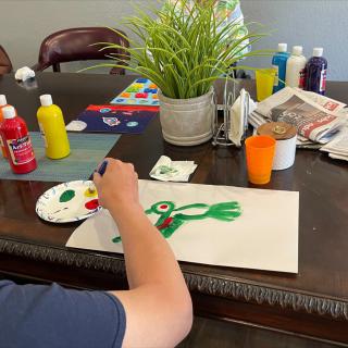 A child painting a colorful picture at a table filled with art supplies.