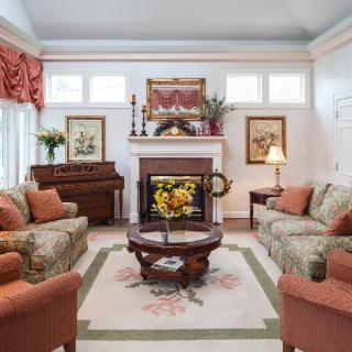 A warmly decorated living room featuring comfortable sofas, a central coffee table, a fireplace adorned with art pieces, and decorative plants.