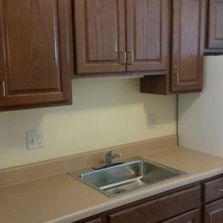 A kitchen with wooden cabinets and a stainless steel sink.