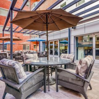 A cozy outdoor patio with a table and cushioned chairs under a large umbrella.