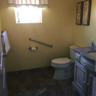 A small bathroom with a toilet, sink, and handrail.