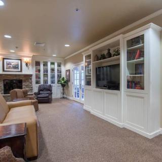 A cozy living room with a fireplace, built-in bookshelves, and a large television.