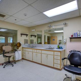 A hair salon interior with mirrors, chairs, and shelves.