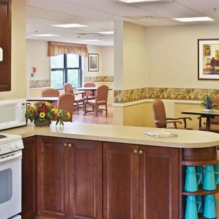 A cozy kitchen with wooden cabinets and a view of a dining area in the background.