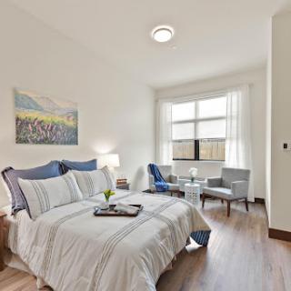 A cozy bedroom featuring modern furniture and ample natural light.