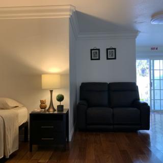 A cozy living space featuring a sofa, a lamp on a side table, and hardwood flooring.