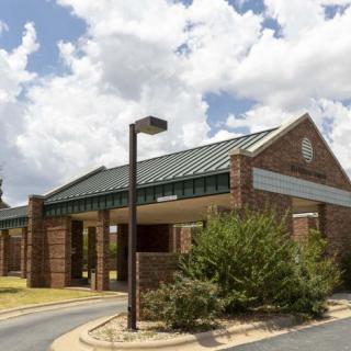 A brick building with a green roof under a cloudy sky.
