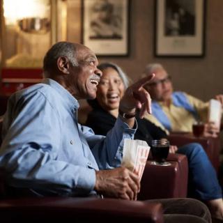 A group of seniors enjoying a movie together, sharing laughter and popcorn.