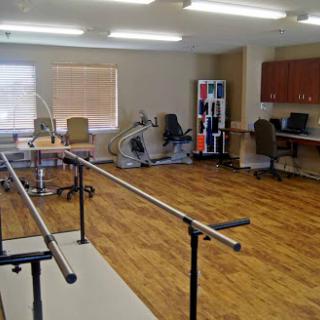A spacious therapy room equipped with rehabilitation tools and exercise bars.