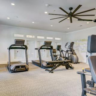 A well-equipped gym featuring treadmills, an elliptical machine, and strength training equipment in a bright, spacious environment.