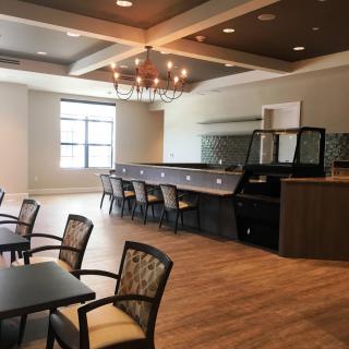A modern bar and seating area with a chandelier and wood flooring.