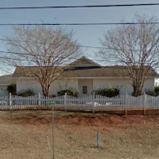 A residential house with a white picket fence and bare trees in the yard.