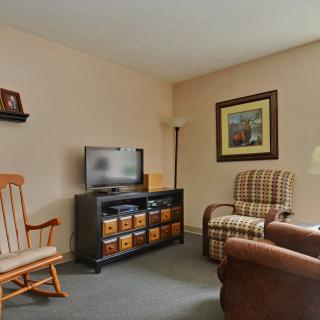 A cozy living room with a television, comfortable chairs, and a rocking chair.