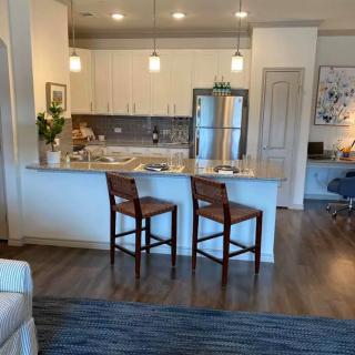 A modern kitchen with an open layout featuring a sleek countertop and bar stools.