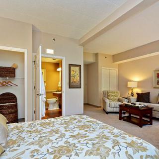A cozy bedroom with a view into a connected living area, featuring elegant furniture and warm lighting.