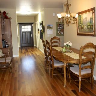 A cozy dining area with wooden flooring and elegant furniture leading to a hallway.