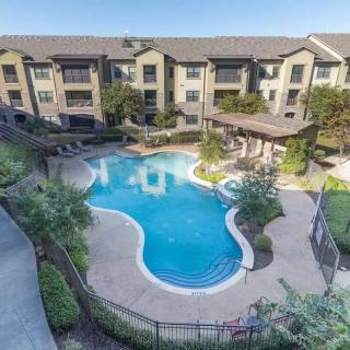 Aerial view of an apartment complex with a central swimming pool surrounded by landscaped pathways.