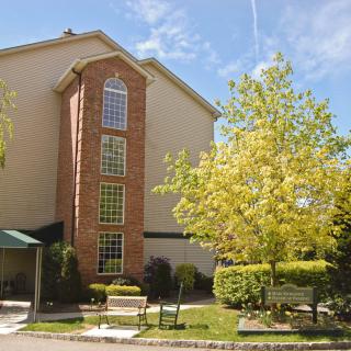 A multi-story building surrounded by trees on a sunny day.