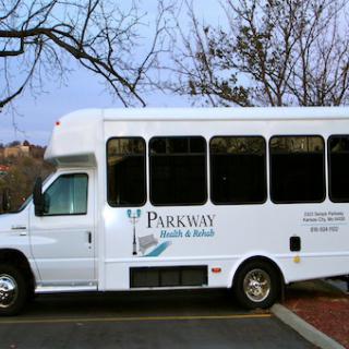 A white bus parked in a lot, branded with Parkway.