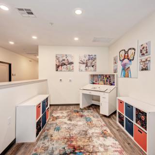 A bright and colorful playroom with children's furniture, wall art, and storage organizers.