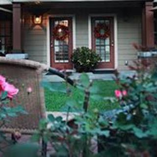 A cozy garden view of a home's patio, framed by flowers and double doors.
