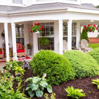 A well-maintained front porch with lush greenery and hanging flower baskets.