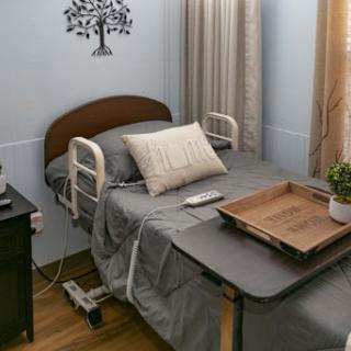 A cozy and organized hospital room setup, featuring a bed with medical equipment, a bedside table, and decorative touches to enhance comfort.