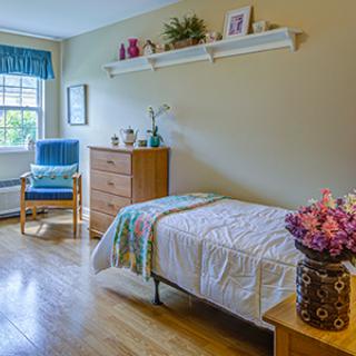 A cozy bedroom with a single bed, wooden furniture, and decorative elements.
