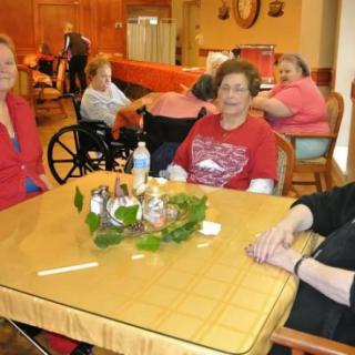 A group of elderly individuals sitting around a dining table in a social setting.