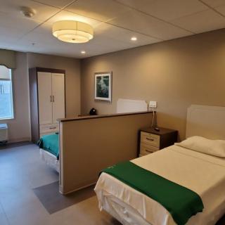 A clean and organized hospital room with two beds separated by a partition.