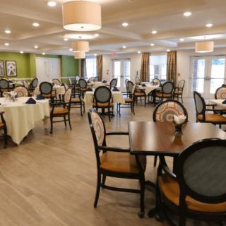 An elegantly designed dining room with neatly arranged tables and chairs, featuring soft lighting.