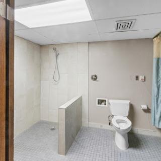 A simple and functional bathroom featuring a shower area and a toilet.