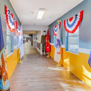 A hallway adorned with patriotic red, white, and blue bunting and various military flags.
