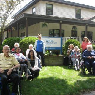 A group of people, including elderly individuals and caregivers, gathered outside a nursing home.