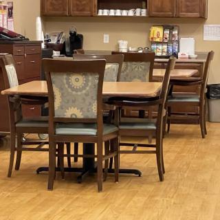 A kitchenette with a dining table and chairs alongside a coffee station.