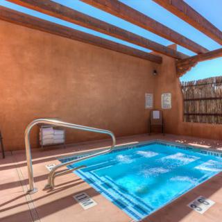 An inviting outdoor hot tub under a wooden pergola on a sunny day.